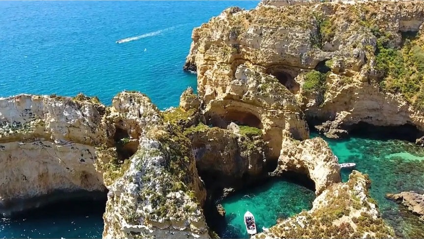 Catamaran e veleiro fundeados junto às falésias douradas da Ponta da Piedade, em Lagos